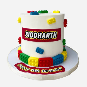 Birthday cake with colorful building block design and personalized name on a white background