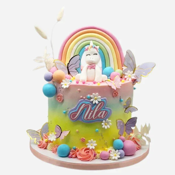 Colorful cake with unicorn, rainbow, and 'Nila' branding on a white background
