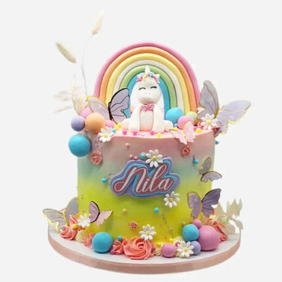 Colorful cake with unicorn, rainbow, and 'Nila' branding on a white background