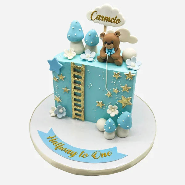Decorative cake with teddy bear and cloud design, featuring the 'Halfway to One' text.