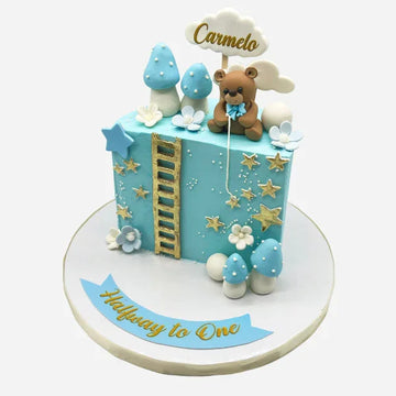 Decorative cake with teddy bear and cloud design, featuring the 'Halfway to One' text.