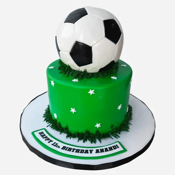 Green birthday cake with a soccer ball on top, featuring grass and stars.