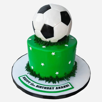 Green birthday cake with a soccer ball on top, featuring grass and stars.