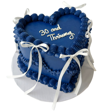 Blue birthday cake with white text and ribbons on a white background